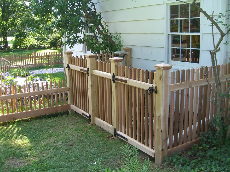 Close view of a cedar garden fence showing the capped post, the mortised rails and the picket spacing, in Lloyd Neck, New York