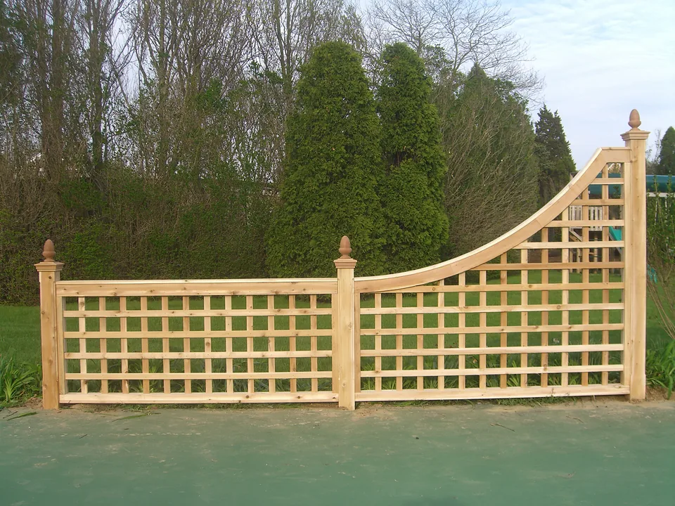 Cedar square lattice tennis court accent panel with a swept curved top rail and acorn-finial posts, beside a tennis court in Southampton, New York