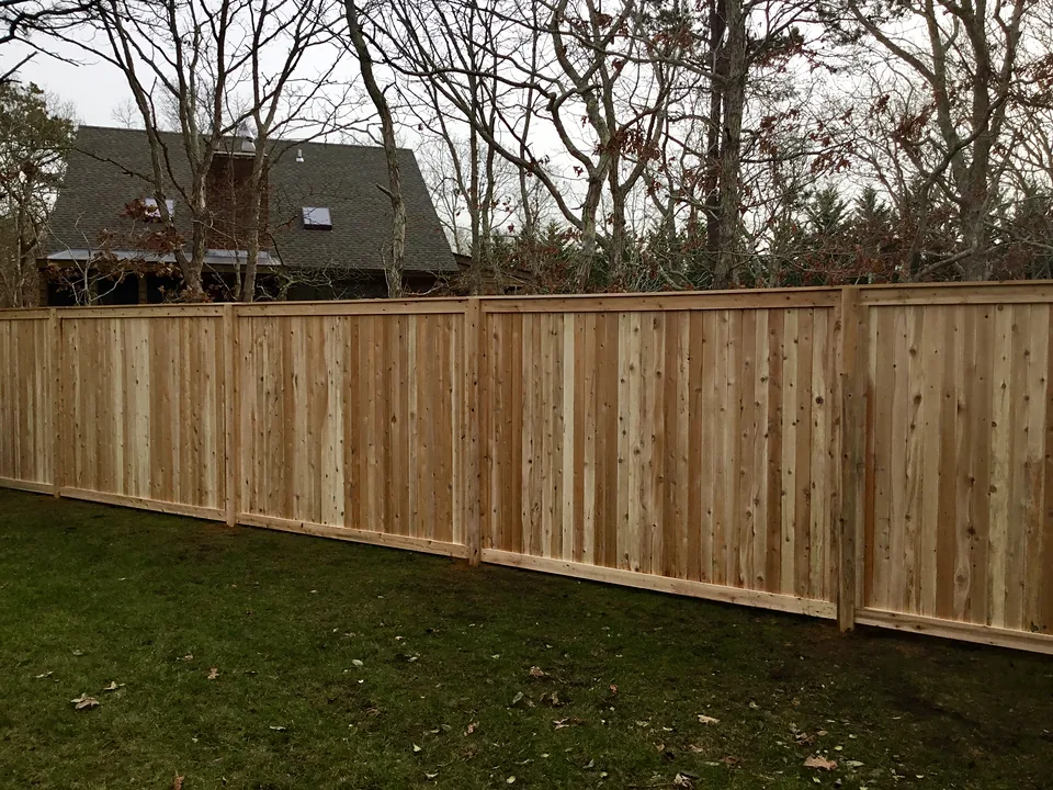 Six-foot natural cedar tongue-and-groove privacy fence with a framed top rail and capped posts, seen along its length in East Hampton, New York