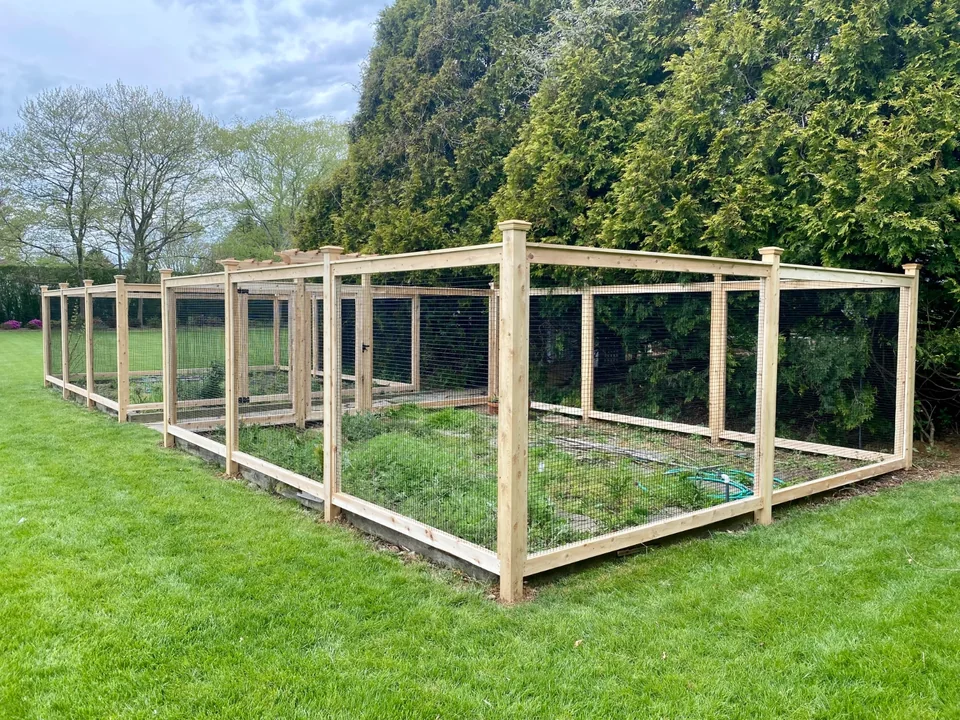 Wide corner view of cedar-framed wire fencing around a Sagaponack garden