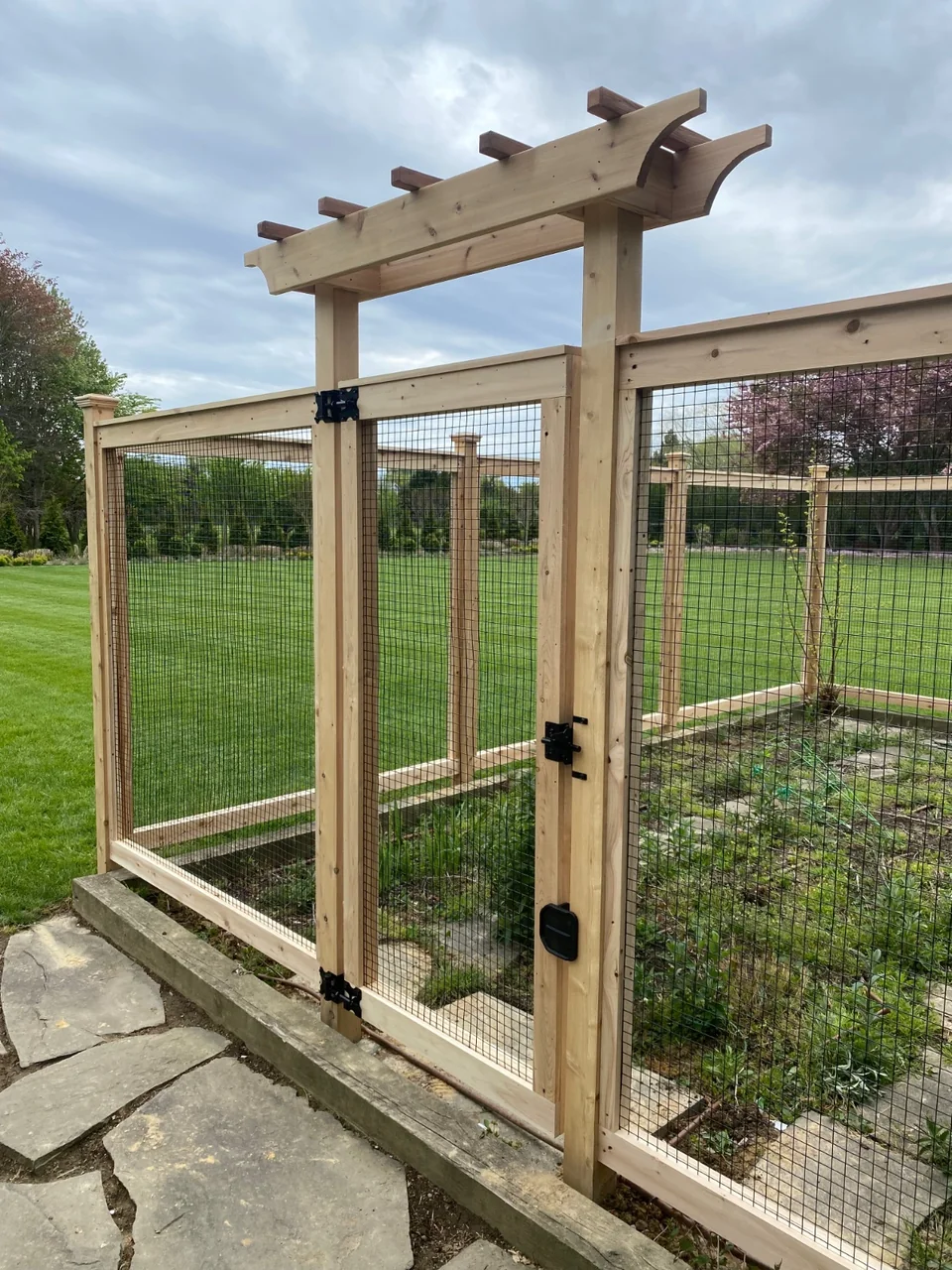 Inside view through a cedar-framed wire garden gate in Sagaponack