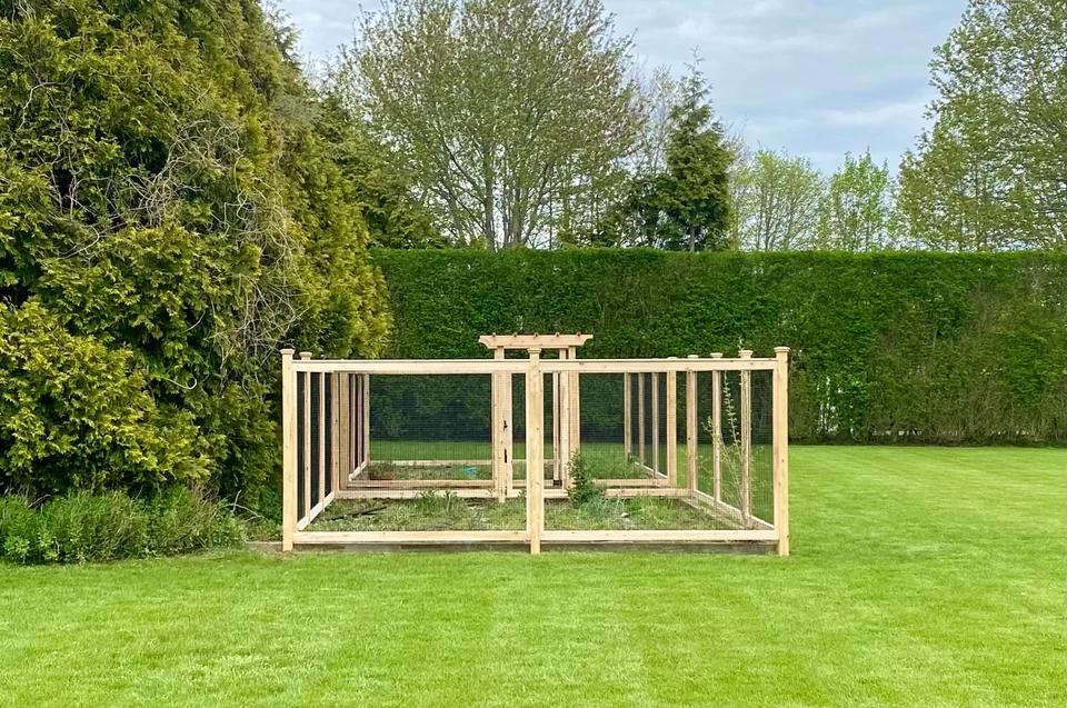 Distant landscape view of a cedar-and-wire garden enclosure in Sagaponack, New York