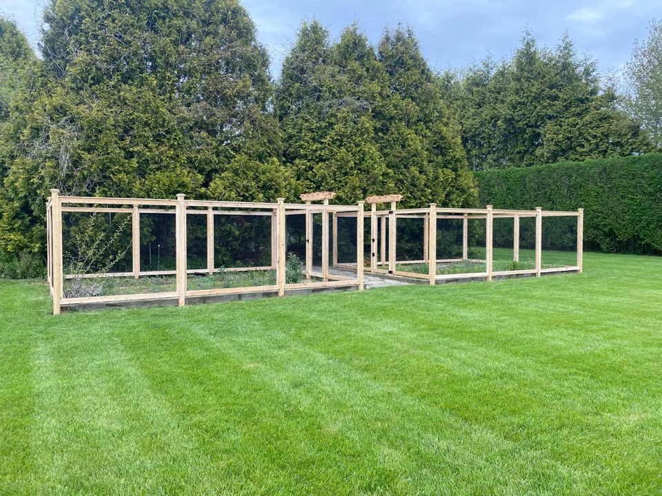 Long cedar and wire fence line protecting a landscaped garden in Sagaponack, New York