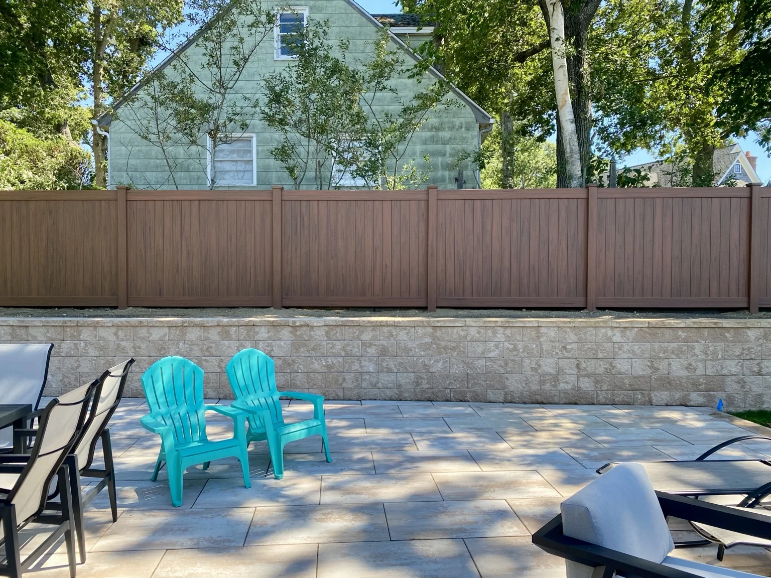 Completed 6-foot cedargrain PVC privacy fence above a retaining wall in Sag Harbor, New York