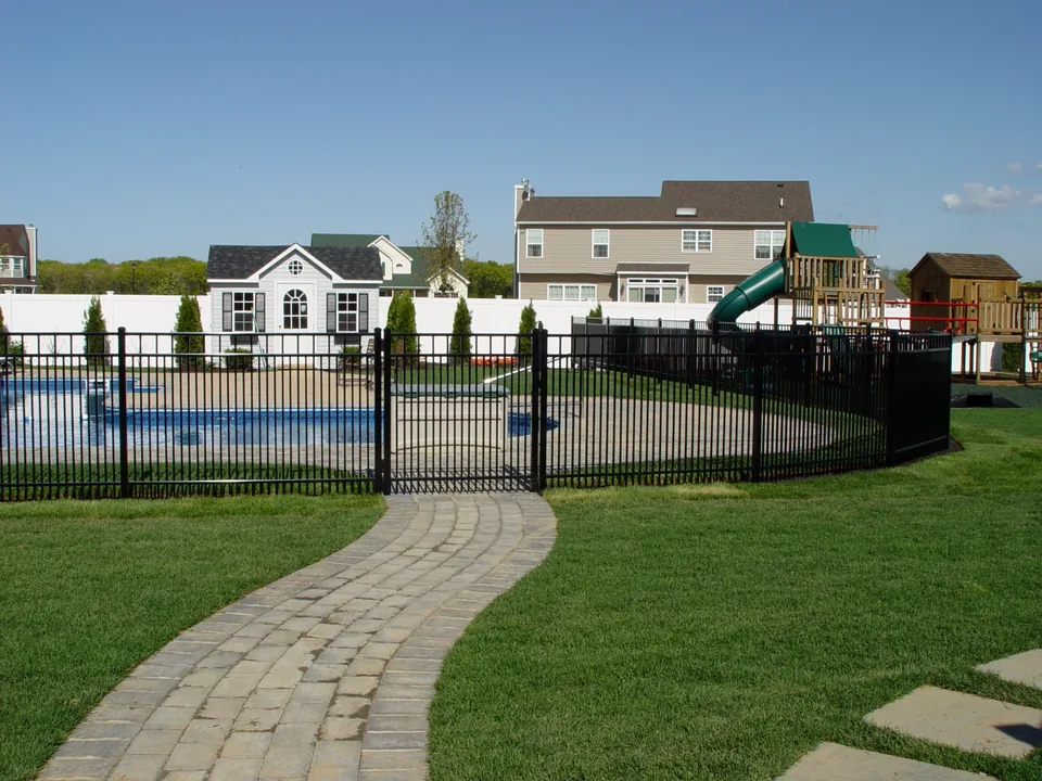 Black aluminum pool gate aligned with a paver walkway in Miller Place, New York