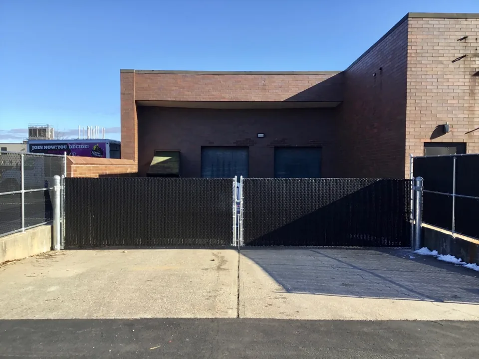 Black privacy-slatted chain link double gates at a commercial property