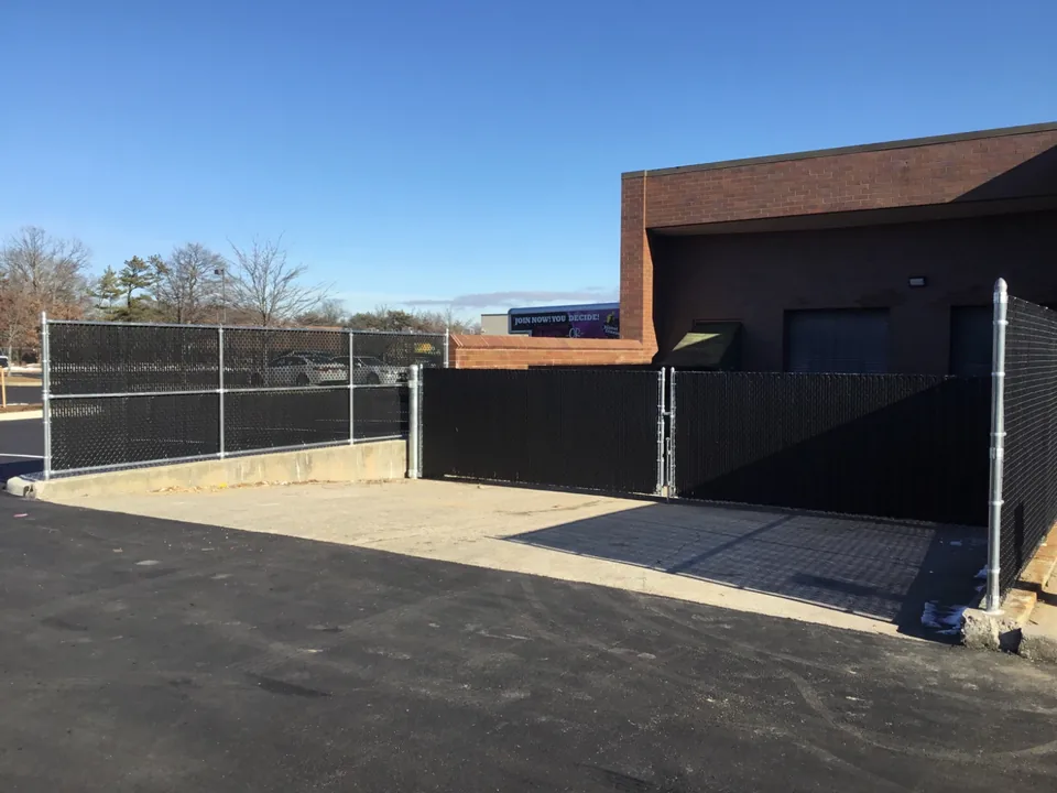 Black privacy-slatted chain link enclosure at a commercial property