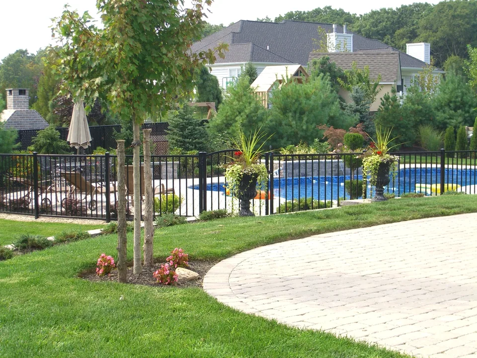 Wide landscaped view of black aluminum pool fencing in Miller Place, New York