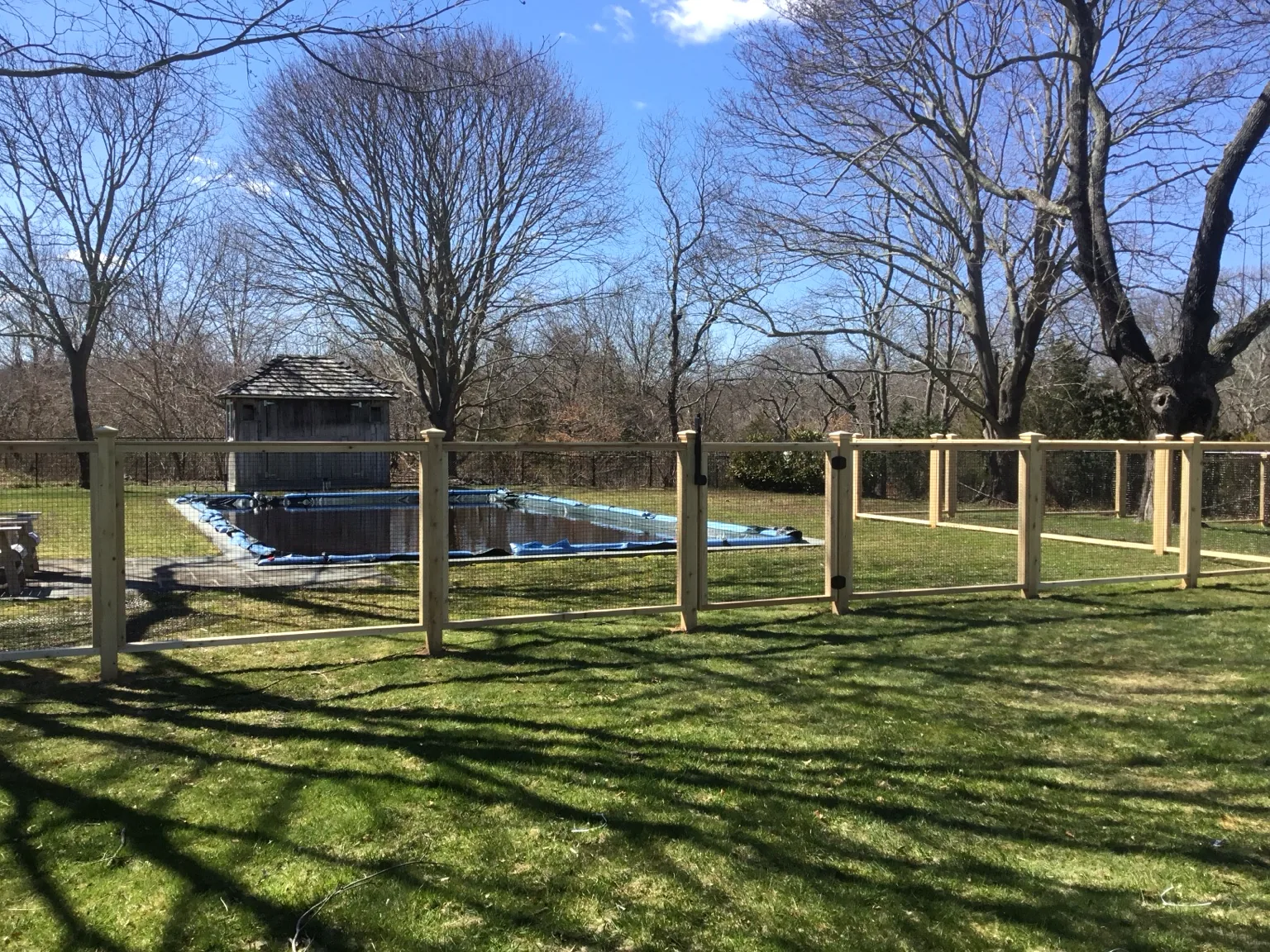 Cedar framed-wire pool gate and open sightline across the pool in Center Moriches, New York.