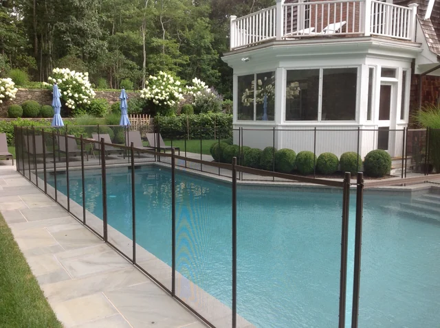 Brown Guardian removable mesh pool fence in a landscaped East Hampton setting