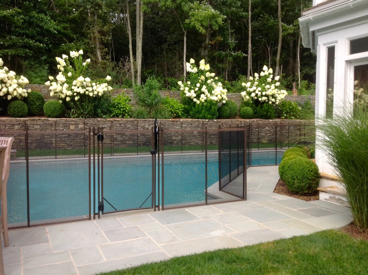House-side brown Guardian pool fence and gate along the stone patio in East Hampton