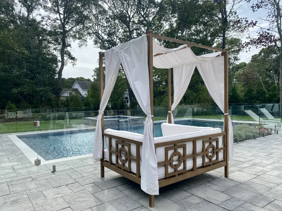 Close view of a frameless glass pool fence and luxury daybed in Remsenburg, New York.