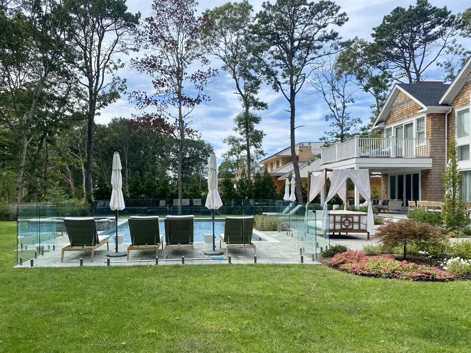 Wide lawn view of a frameless glass pool fence installation in Remsenburg, NY.