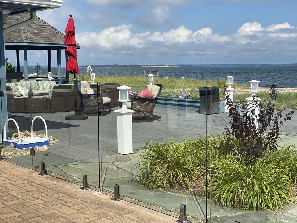 Frameless glass pool fencing preserving the waterfront view from a deck in Southold, NY.
