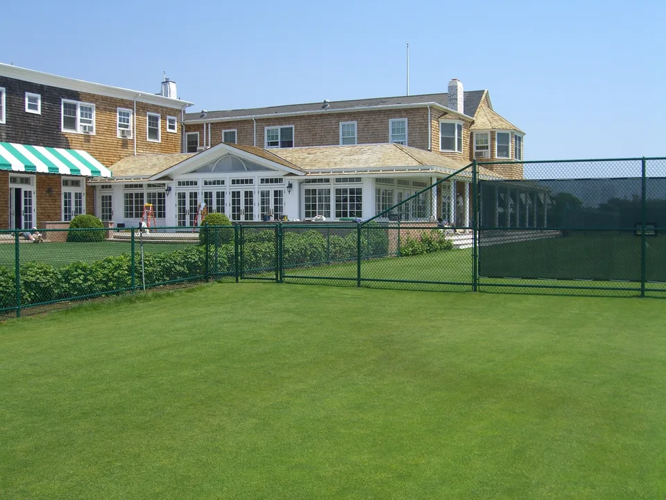 Green chain link gates and tennis court enclosure at a private club in Southampton