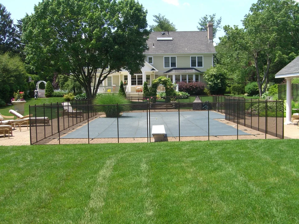Removable mesh pool safety fence enclosing a backyard pool in Melville, New York