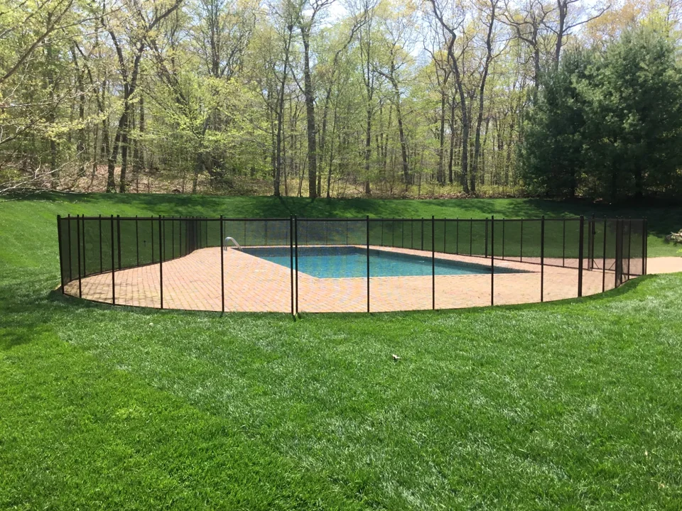 Guardian Premier brown mesh pool fence viewed across the lawn in a large East Hampton backyard