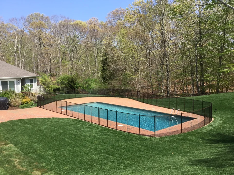 Brown Guardian Premier pool fence with red brick patio lawn and wooded East Hampton landscape