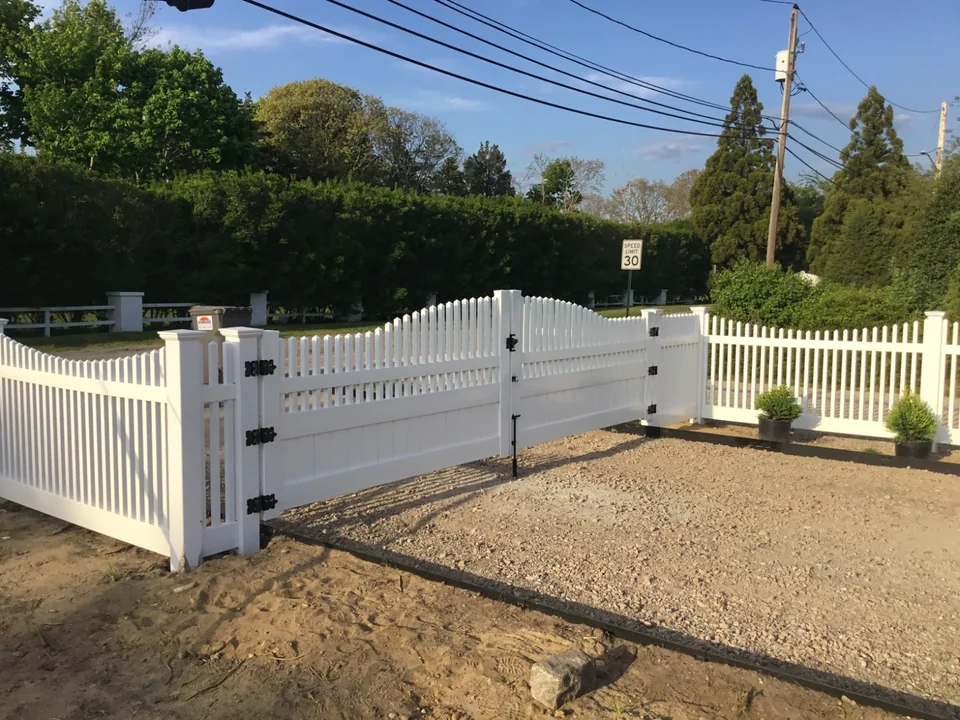 Job-site view of a wide custom PVC driveway gate during a Hampton Bays fence installation.