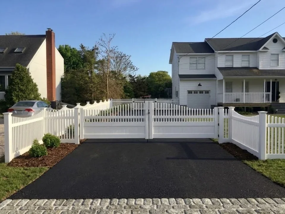 16-foot reinforced white PVC driveway gate at a Hampton Bays home with a newly paved asphalt driveway.