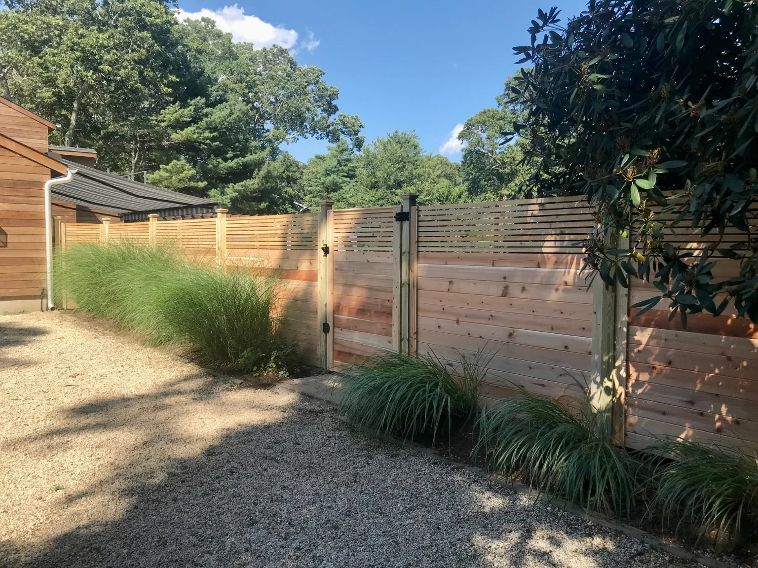 Custom horizontal cedar fence and gate beside established landscaping in Westhampton, New York