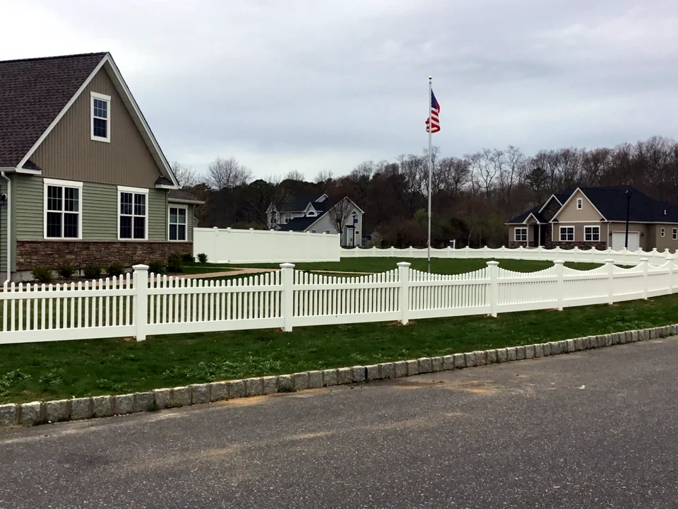 Long angled run of three-foot white scalloped PVC picket fencing in Manorville, New York.