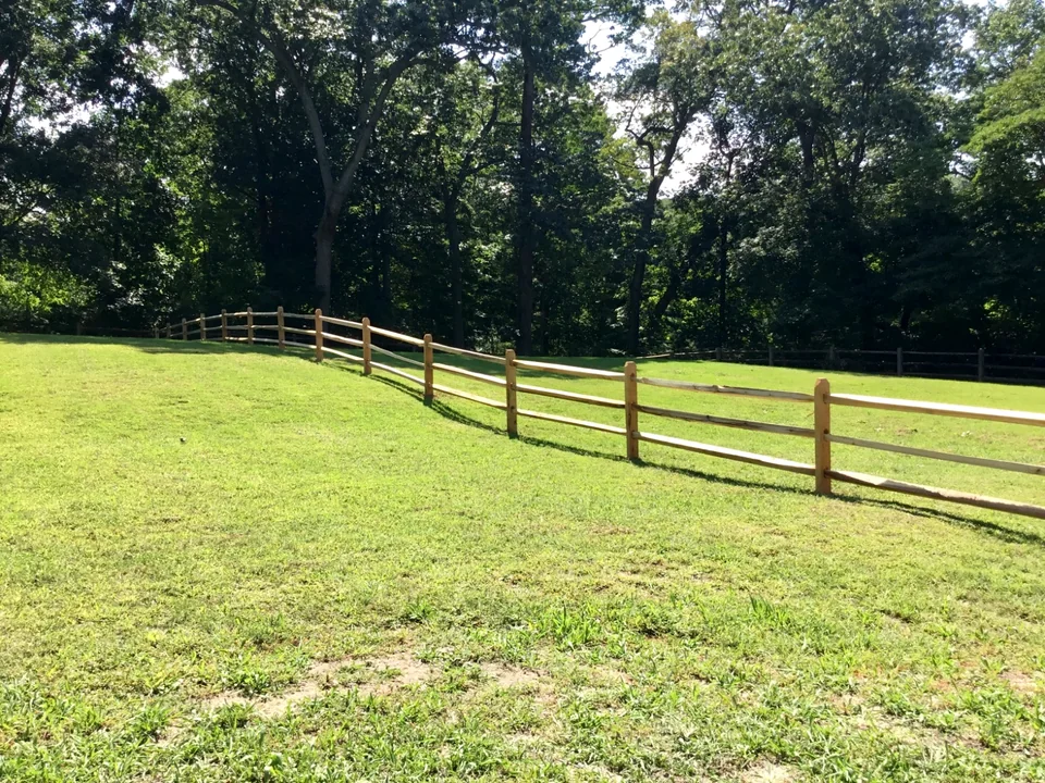 Split rail fence following a sloping lawn in Oyster Bay, New York.