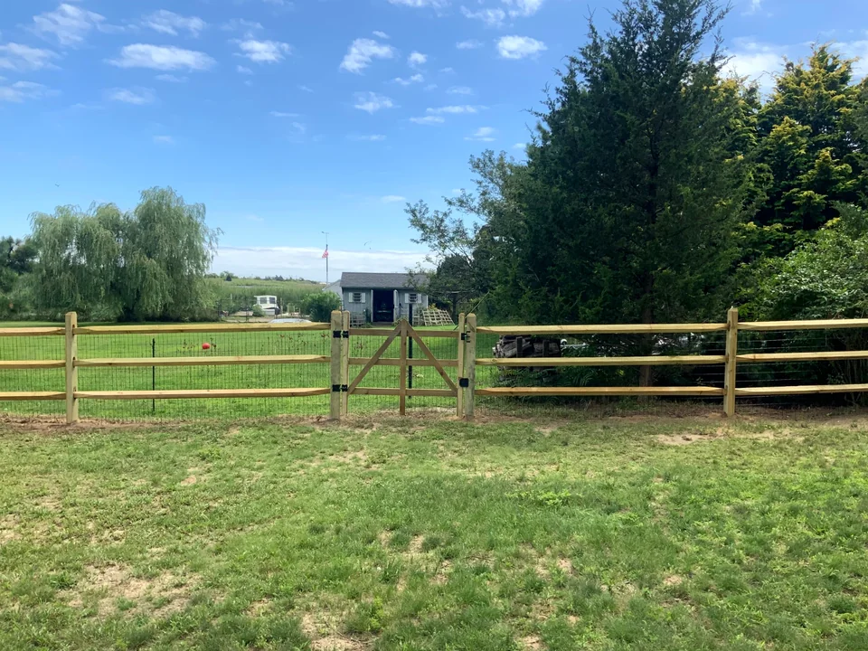 Three-rail split rail fence and gate opening in Patchogue, New York.