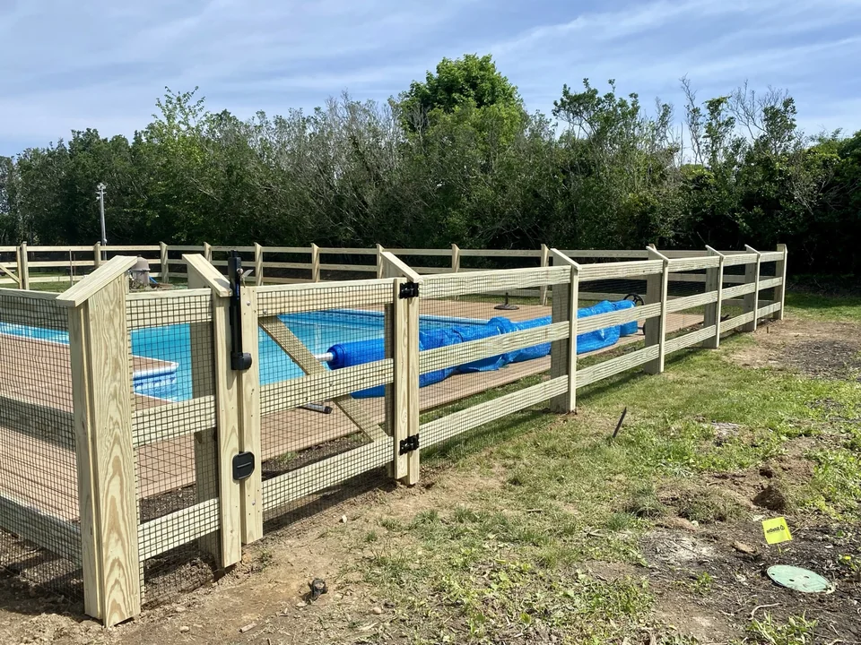 Close view of custom pool gate and long pressure-treated fence run