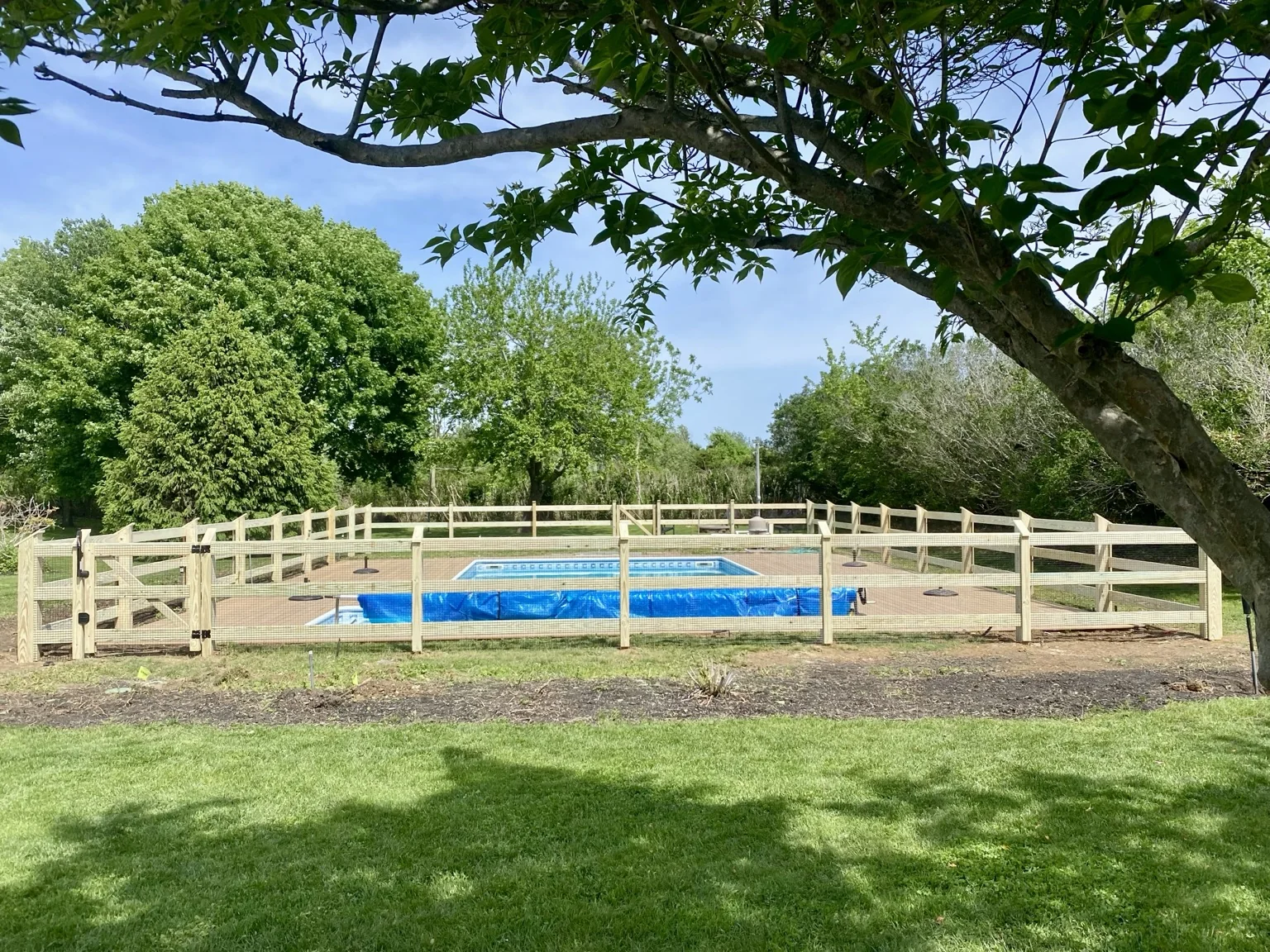 Wide landscape view of a pool-code-compliant post and rail wire fence in Aquebogue, New York