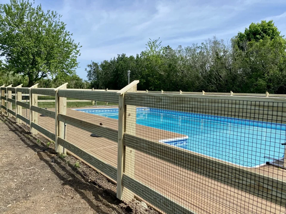 Poolside detail of black welded wire secured to pressure-treated rails