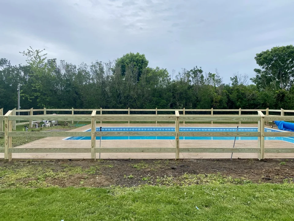 Straight elevation of pressure-treated post and rail wire pool fence