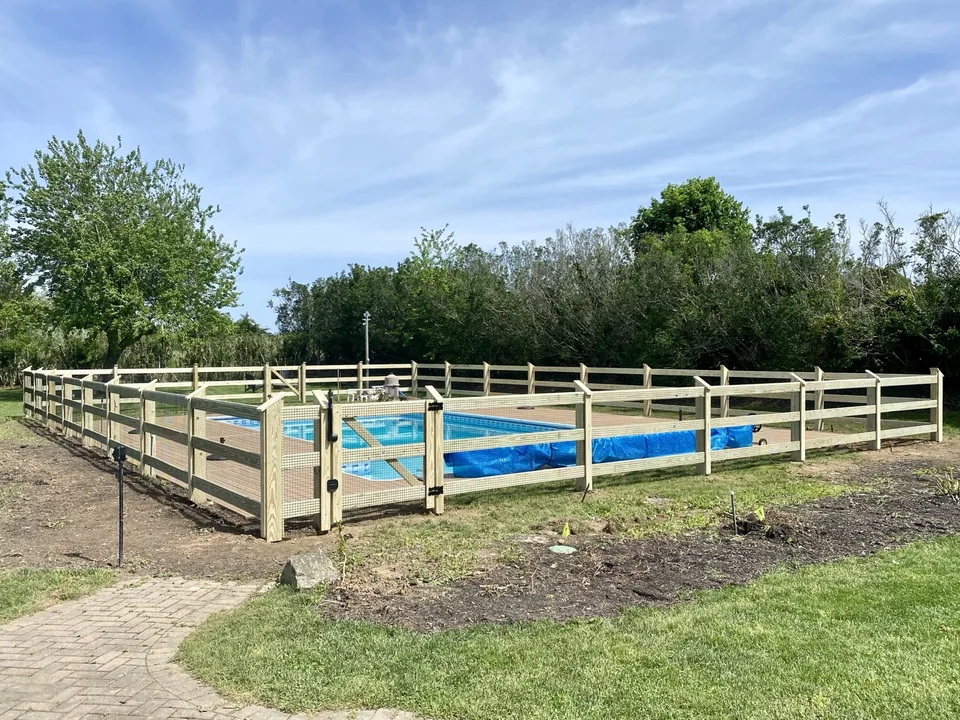 Wide view of post and rail wire pool fence with custom gate