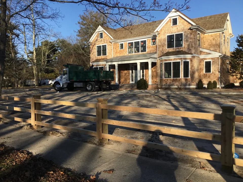 Custom three-rail board fence wrapping a Remsenburg residential property.