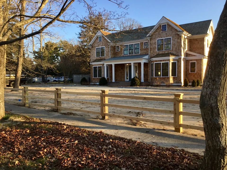 Street-angle view of a custom cedar and pressure-treated board fence in Remsenburg, New York.