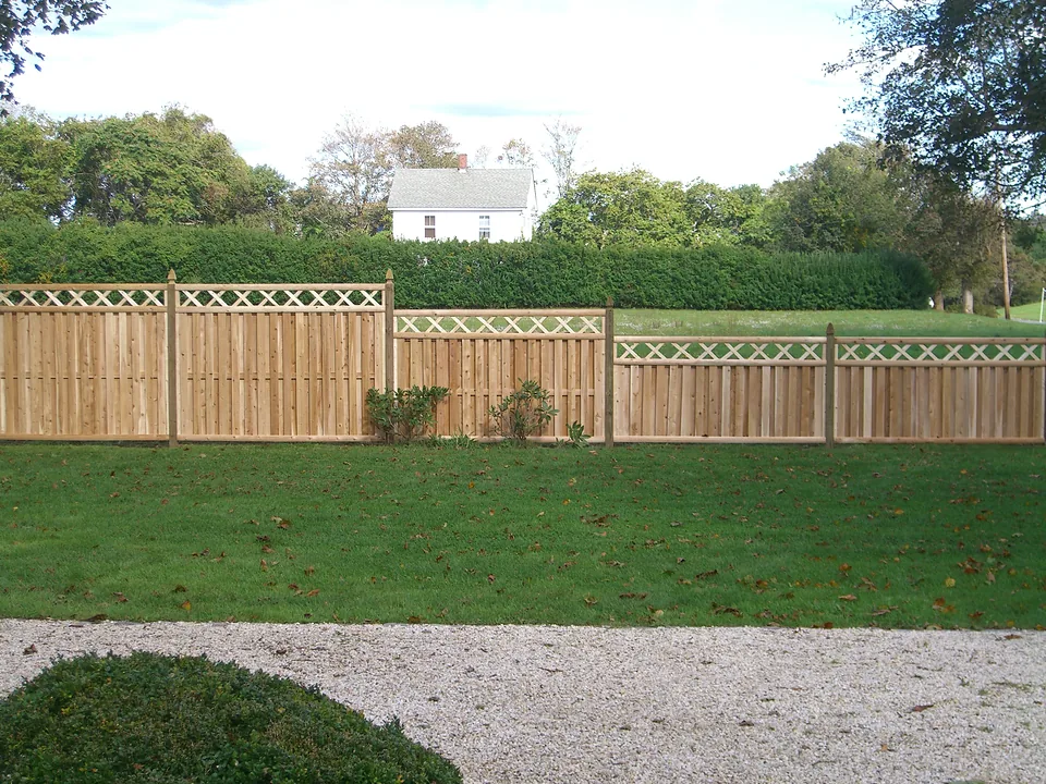 Shadow box cedar fence with X-lattice topper stepping down from six feet to four feet across a lawn in Southampton, New York