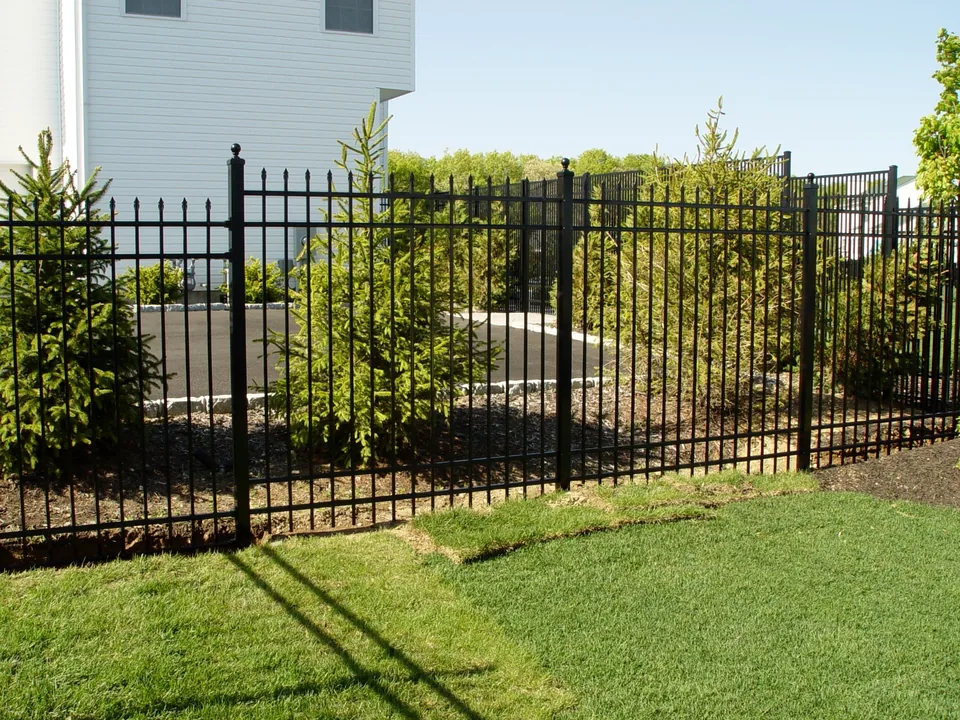 Six-foot spear-top aluminum fence passing landscaped plantings in Miller Place, New York