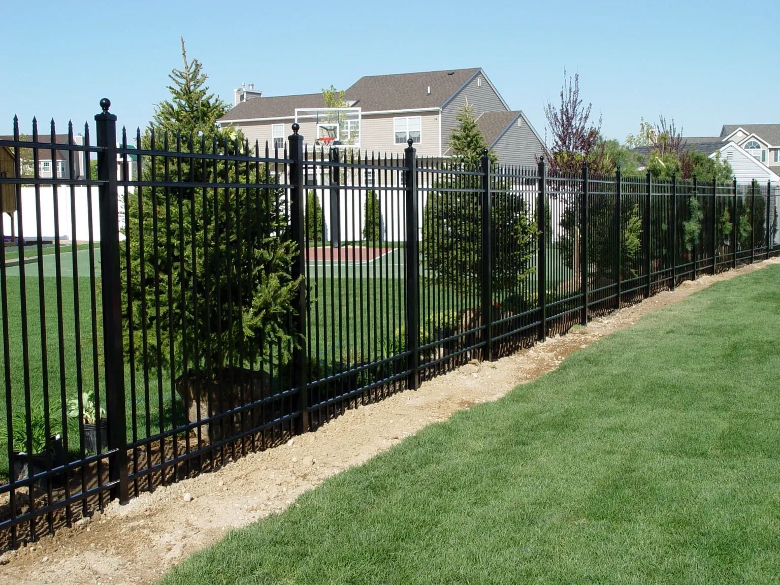 Long run of 6-foot black spear-top aluminum fence along a landscaped property line in Miller Place, New York
