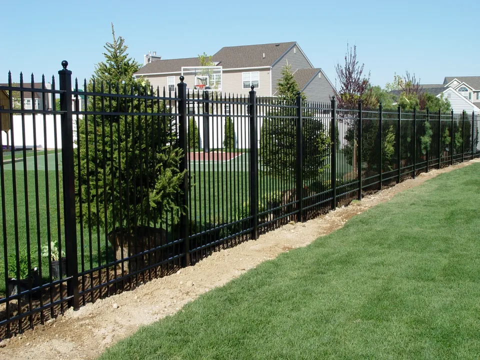 Long run of 6-foot black spear-top aluminum fence along a landscaped property line in Miller Place, New York