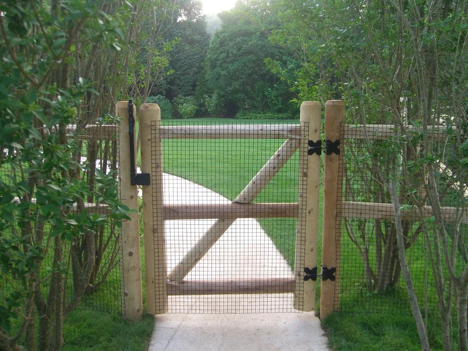 Round cedar post and rail walk gate with wire in Southampton, New York.