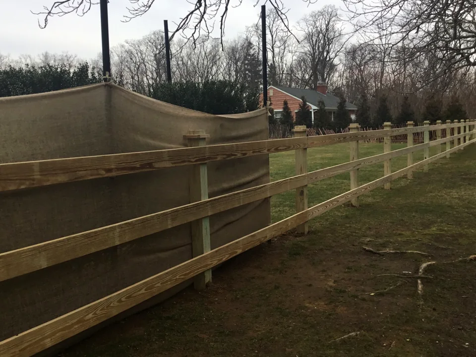 Rear view of pressure-treated three-rail board fencing in Southold, New York.