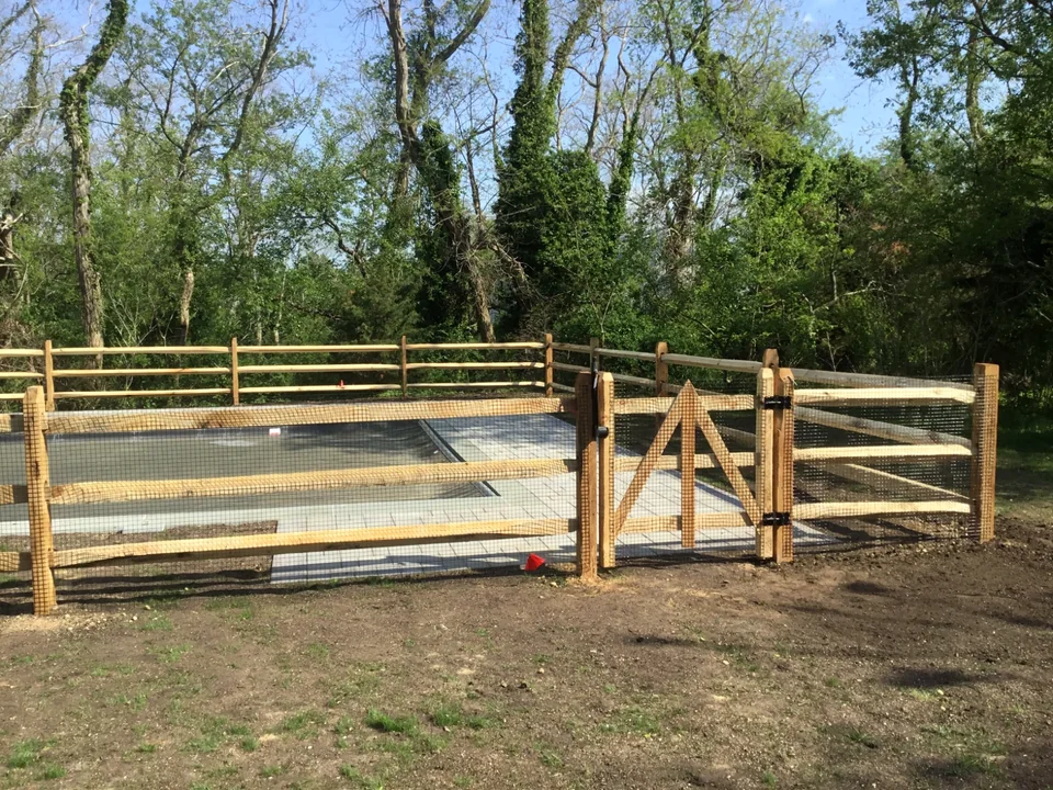 Custom gate integrated with split rail fencing in St. James, New York.