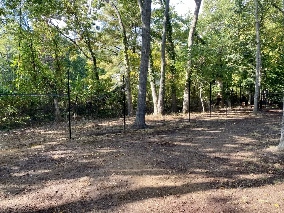 Long run of stacked black deer fence between trees