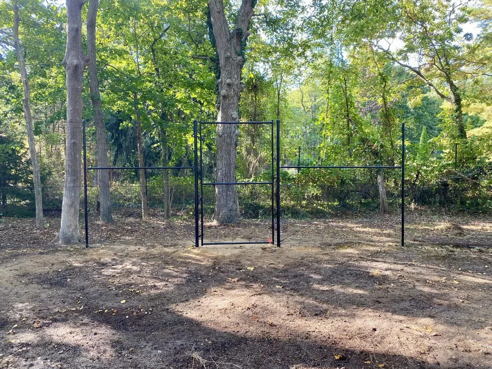 Stacked black deer fence following a wooded property perimeter