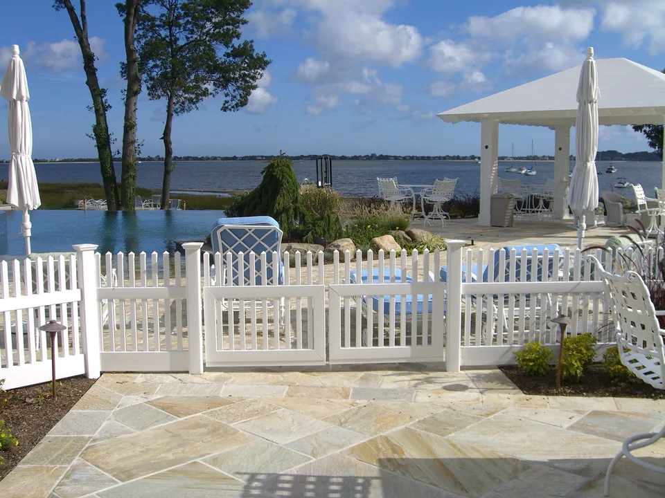 White PVC picket gate overlooking a waterfront pool and harbor in Centerport, New York