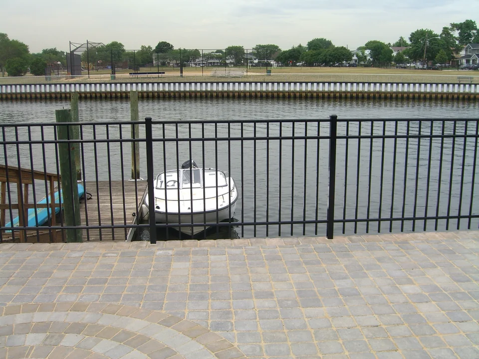 Black aluminum waterfront fence with a boat and canal beyond at a Seaford, New York home