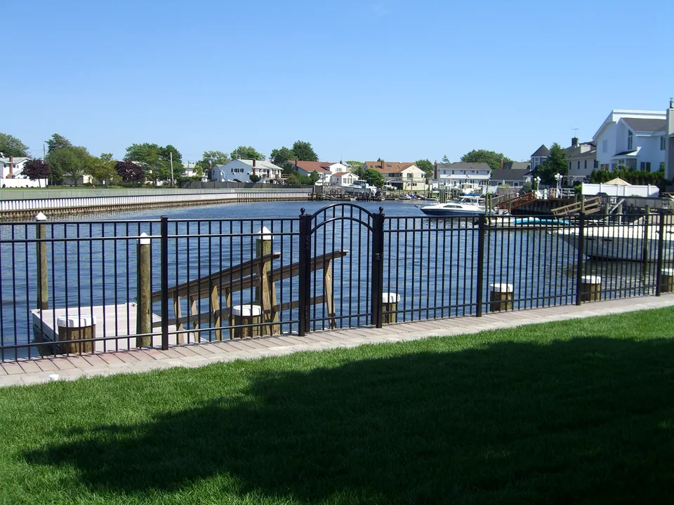 Black aluminum fence installed along a wood bulkhead at a waterfront property in Seaford, New York