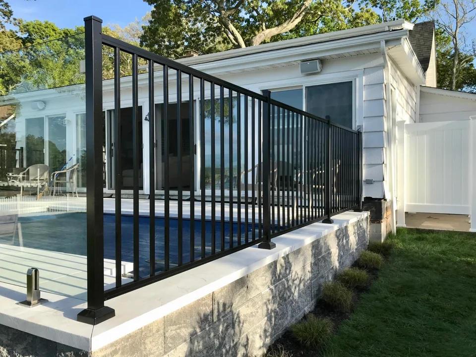 Black aluminum railing meeting the frameless glass installation at a raised patio in Southold, New York.