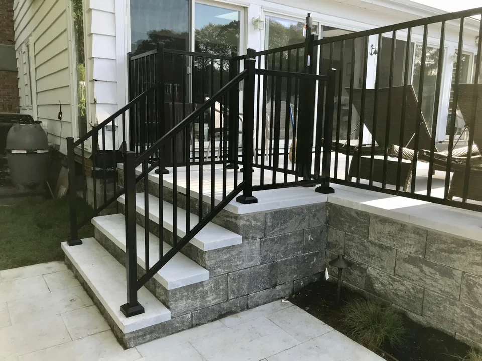 Black aluminum railing and gate at steps beside a raised pool patio in Southold, New York