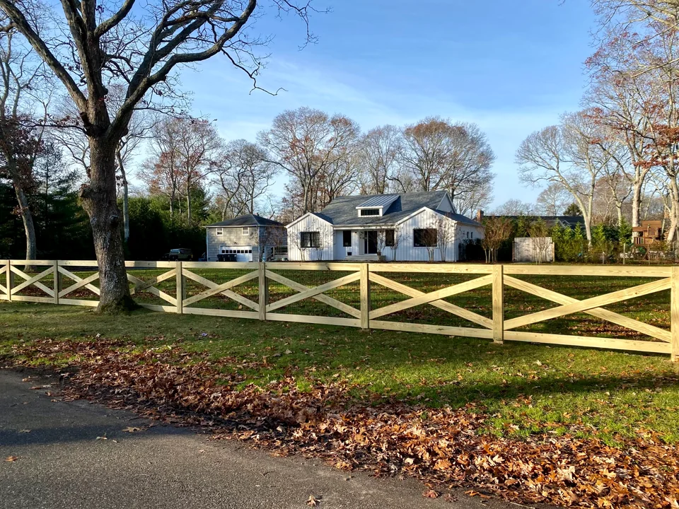 Custom crossbuck fence turning along a Westhampton property corner.